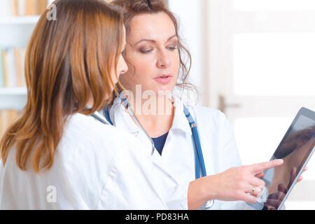 Two women doctors looking on tablet pc and discussing tests result Stock Photo
