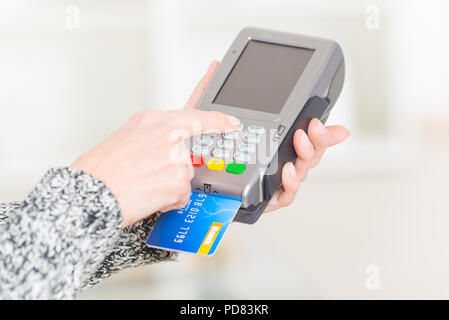 Entering PIN code on wireless payment terminal with inserted redit or debit card Stock Photo