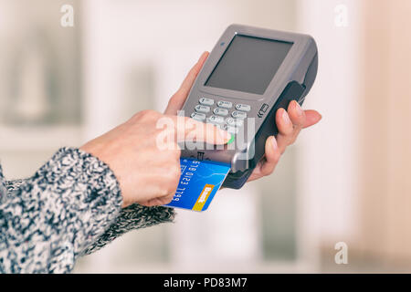 Entering PIN code on wireless payment terminal with inserted redit or debit card Stock Photo