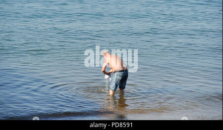 Brighton UK 7th August 2018 - Time for a dip in the sea off Brighton beach as the hot sunny weather continues on the south coast but it is forecast to cool down throughout Britain over the next few days Credit: Simon Dack/Alamy Live News Stock Photo