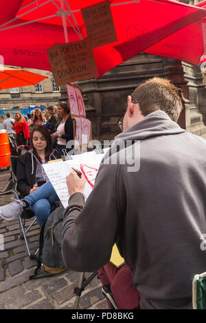 Edinburgh, Scotland, UK. 7th August 2018. Street acts and artists, alongside promoters of Fringe Festival events, ply the streets of Edinburgh Festival, providing entertainment and amusement to the many visitors to the Fringe. This ambidextrous artist produced portraits in a two minute sitting. Credit Joseph Clemson, JY News Images/Alamy. Stock Photo