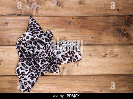 Scarf with leopard print on a wooden background. Natural colors and natural ornament in fashion. Free space for text. Top view. Stock Photo
