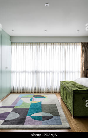 Lime green velvet blanket box with colourful rug and closed blinds Stock Photo