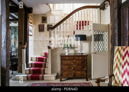 Wood panelled entrance hall with red carpet runner, 18th century oak wood chest and modern lamp Stock Photo