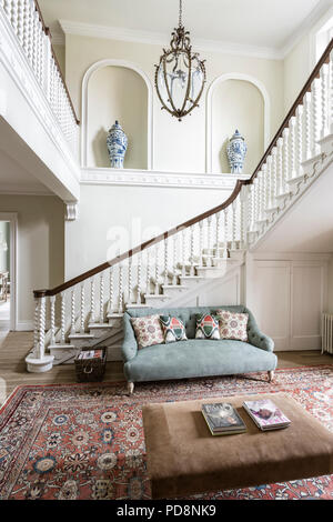 Chinese urns in staircase alcove with light green buttoned sofa Stock Photo