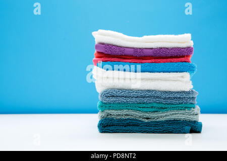 Photo of multi-colored bath towels on empty blue background. Stock Photo
