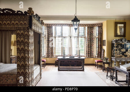 Four postered bed upholstered in 17th century flame stitch embroidery with desk at leaded window Stock Photo