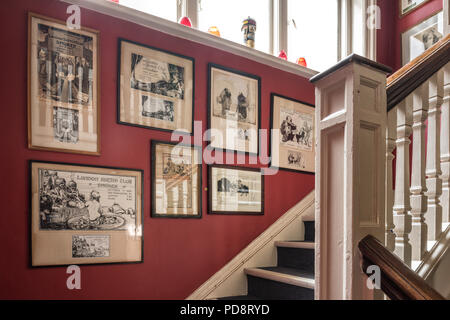 Old framed cartoons on the red staircase wall of the London Sketch Club Stock Photo