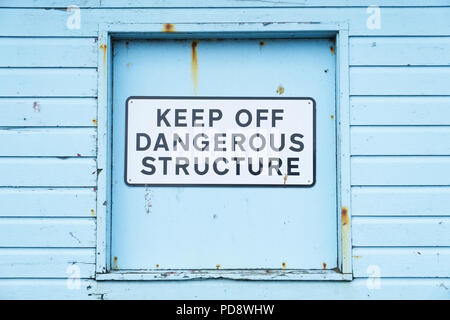 Keep off dangerous structure sign on duck egg coloured wooden wall Stock Photo
