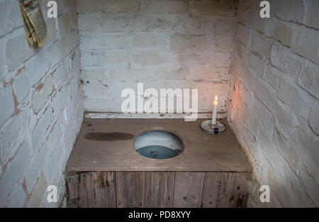 Interior of old-fashioned, non-flushing bucket toilet in brick-built outhouse. Pail privy, pail closet close up (Rochdale system). Toilet newspaper. Stock Photo