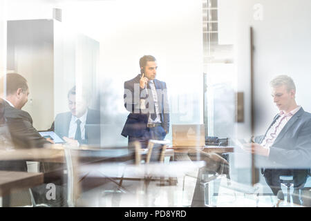 Businessman talking on a mobile phone on corporate office. Stock Photo