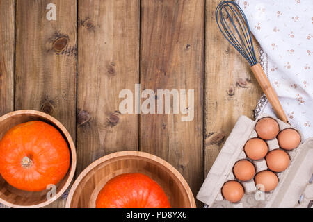 Pumpkins in wooden cups on a wooden background and eggs. Free space for text. Top view. Stock Photo