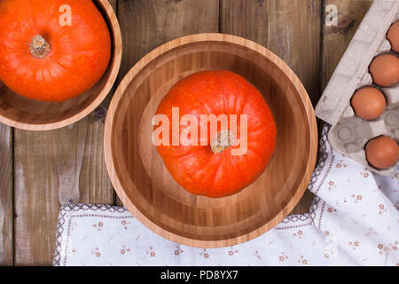 Pumpkins in wooden cups on a wooden background and eggs. Free space for text. Top view. Stock Photo