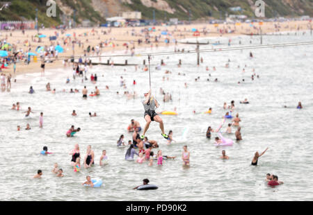 A person takes a ride on a zip wire on Bournemouth beach, as the hot weather continues. Stock Photo