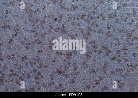 Background texture featuring a close-up view of a corroded and pitted metal wheel with blue, gray, and purple color tones Stock Photo