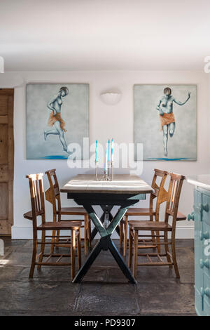 Pair of paintings by James Wedge flanking a wooden farmhouse style table Stock Photo