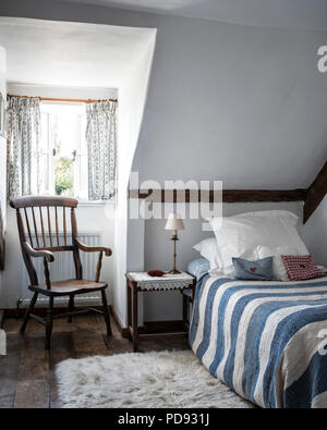 Vintage striped quilt and antique windsor chair in attic guest bedroom Stock Photo