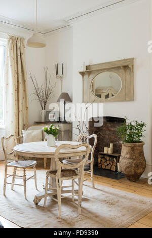 White circular table and rattan dining chairs in bright and airy sitting room Stock Photo