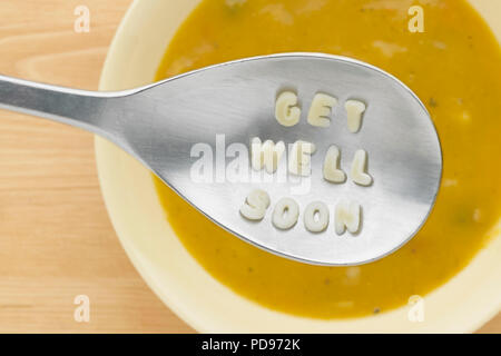 'Get well soon' in pasta shapes on spoon over bowl of soup Stock Photo