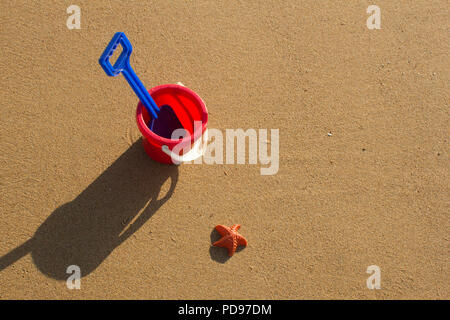 A bucket and spade sitting on a sandy beach during a sunny day in Sutherland, Highlands Scotland. Stock Photo