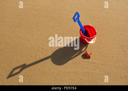 A bucket and spade sitting on a sandy beach during a sunny day in Sutherland, Highlands Scotland. Stock Photo