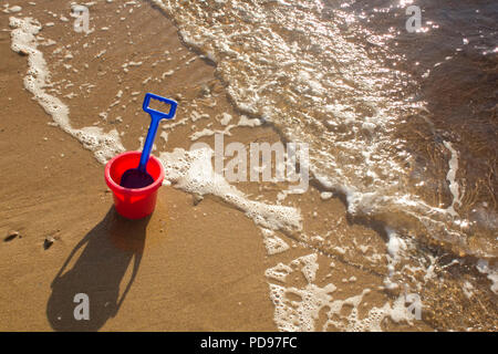 A bucket and spade sitting on a sandy beach during a sunny day in Sutherland, Highlands Scotland. Stock Photo