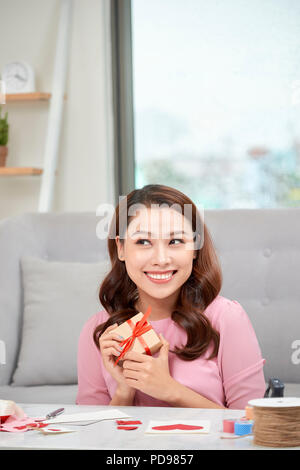 Happy young woman pressing gift box to her chest Stock Photo
