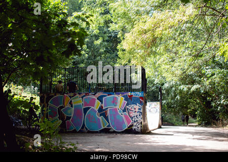 Teens relaxing in an urban skate park (skate ramp) covered in graffiti built in the woods along the Parkland Walk in North London Stock Photo