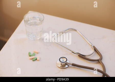 Pharmacy background on a white table. Tablets on a white background. Pills. Medicine and healthy. Close up of capsules. Stethoscope on a white wooden  Stock Photo