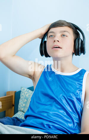 Teenage boy playing a video game while on his bed Stock Photo