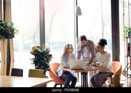 Young people man and women coworking together at creative stylish office sitting at the table browsing laptop looking for new ideas concentrated Stock Photo
