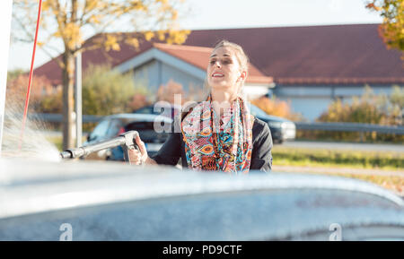 Woman using high pressure nozzle to clean her car Stock Photo