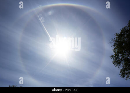 Stockholm, Sweden - August 6 2018: Circular rainbow around the sun - which has an airplane flying into it. Meteorological phenomenon. Stock Photo