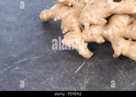 Whole ginger roots on dark old stone background table, space for text. Stock Photo