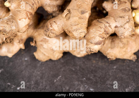 Whole ginger roots on dark old stone background table top view space for text. Stock Photo