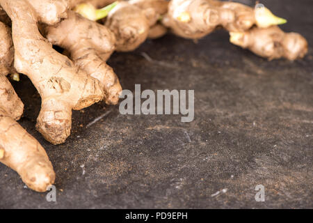 Whole ginger roots on dark old stone background table top view space for text. Stock Photo