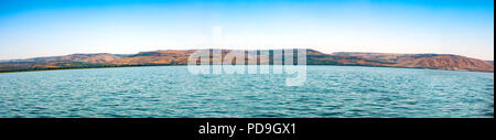 Wide panoramic seascape of the glowing blue green Sea of Galilee from a boat looking east towards the Golan Heights, an area of much conflict, on the  Stock Photo
