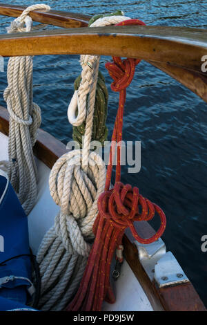 Wooden sailboat on the blue mediterranean sea. Details of a classic beautiful sailing yacht with ropes, knots and wood plank on deck background. Stock Photo