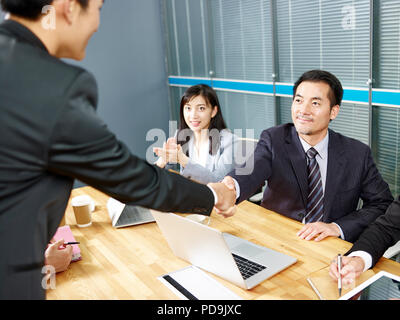 two asian corporate executives shaking hands during meeting in office. Stock Photo