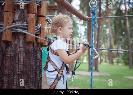 Little girl hangs up carbine in a track in the rope park. Stock Photo