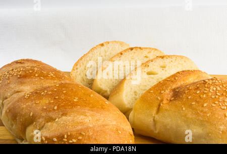 sliced whole wheat breads on a chopping Board against a white linen tablecloth Stock Photo