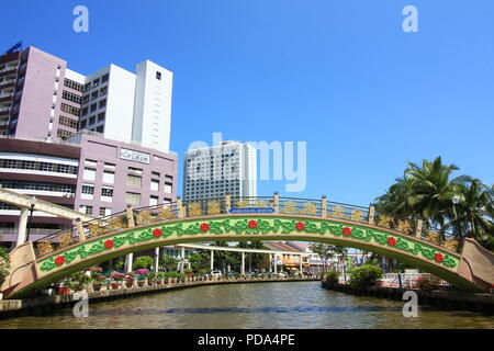 The colorful Kampong Morten bridge along Melaka River Cruise with some modern building at the background,tourist enjoy sightseeing on cruising boats Stock Photo