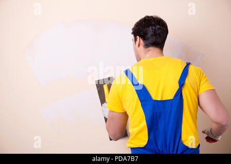 Young contractor employee applying plaster on wall Stock Photo
