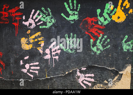 Many colorful palm prints on black concrete wall, abstract background texture Stock Photo