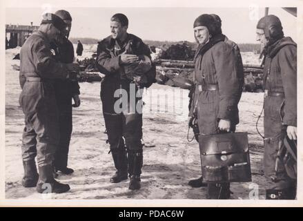 Image from the photo album of Oberleutnant Oscar Müller of  Kampfgeschwader 1: After their return from a mission to Dno Airfield in Russia, Oscar Müller (third from left) and his crew brief a member of the ground crew. The crewman holding the briefcase is Feldwebel Alfred Koltermann, Oscar Müller’s Observer; the crewman with spectacles is Unteroffizier Philipp Höchst, Oscar Müller’s Radio Operator. 1942. Stock Photo