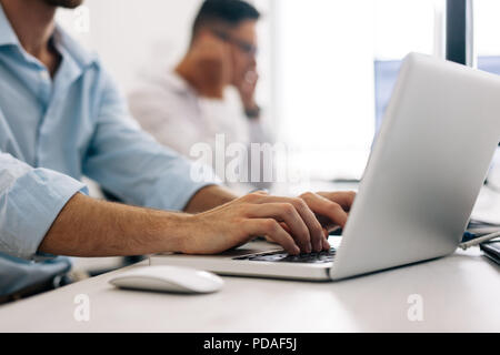 Software developers at office working on computers. Close up of an application developer working on a laptop in office. Stock Photo