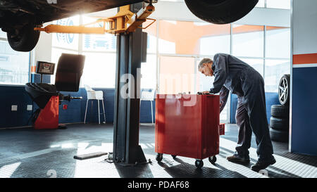 Mechanic working in the garage and looking for tools in toolbox. Repairmen working in service station. Stock Photo