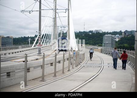 PORTLAND, OREGON, MAY 16 2017, On the Tilikum Crossing bridge with a Streetcar, a bicyclist, and people walking & jogging. Stock Photo