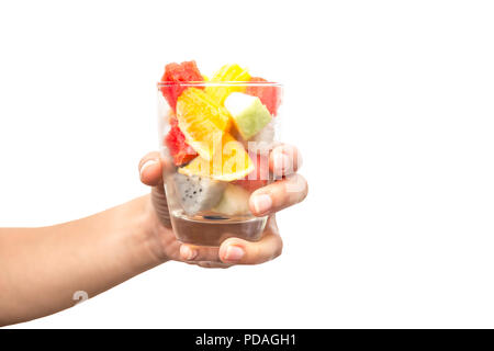 Hand holding fresh fruit salad in a glass isolated in white background clipping path. Stock Photo