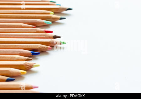 Wooden color pencils on empty white paper. Minimalist template with copy space close up macro. Stock Photo